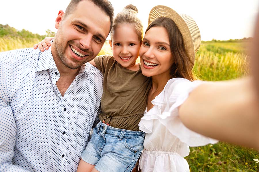 Personal Insurance - Portrait of Joyful Family with Young Daughter Enjoying a Trip to the Countryside During the Summer